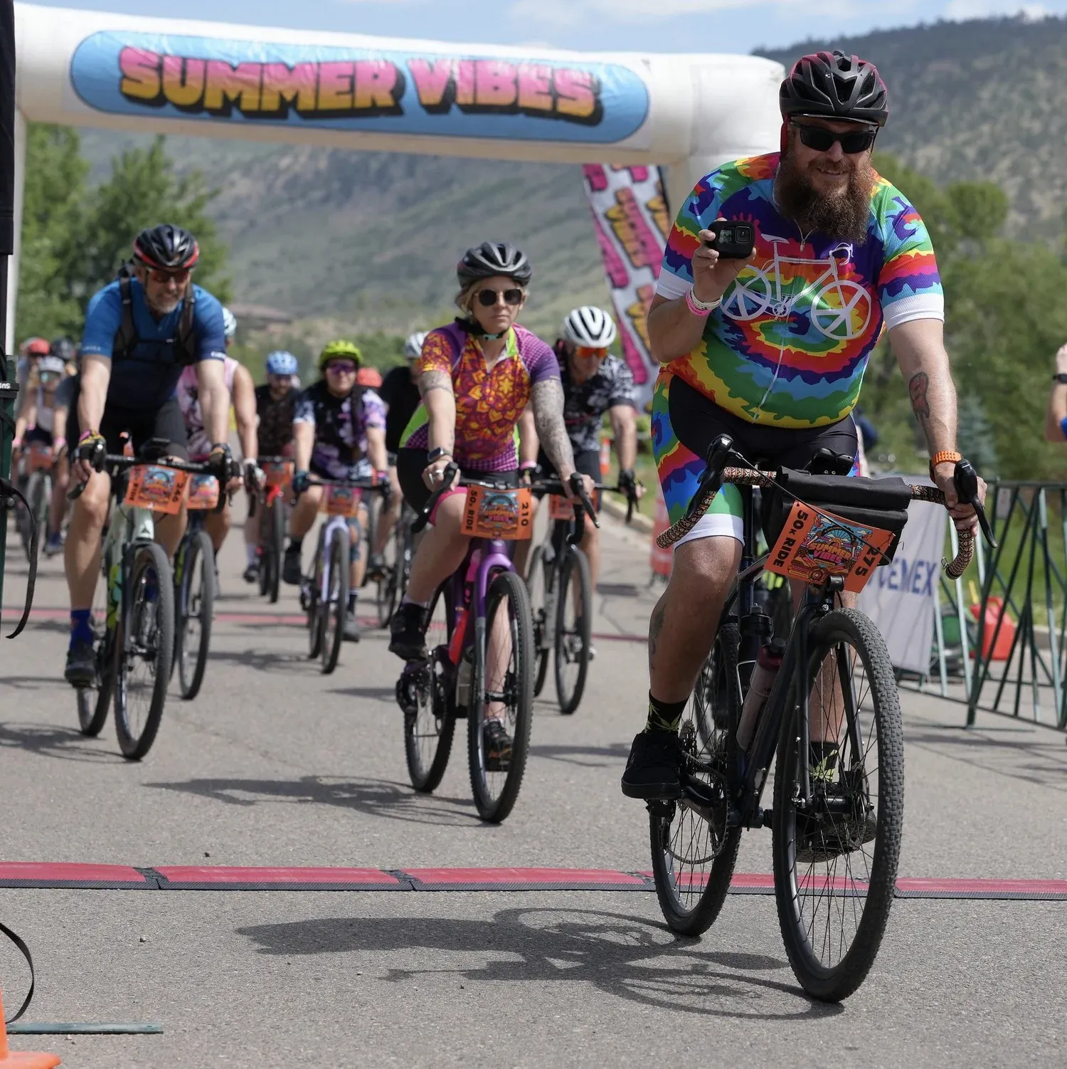 Rider in a tie dye jersey crossing the finish line