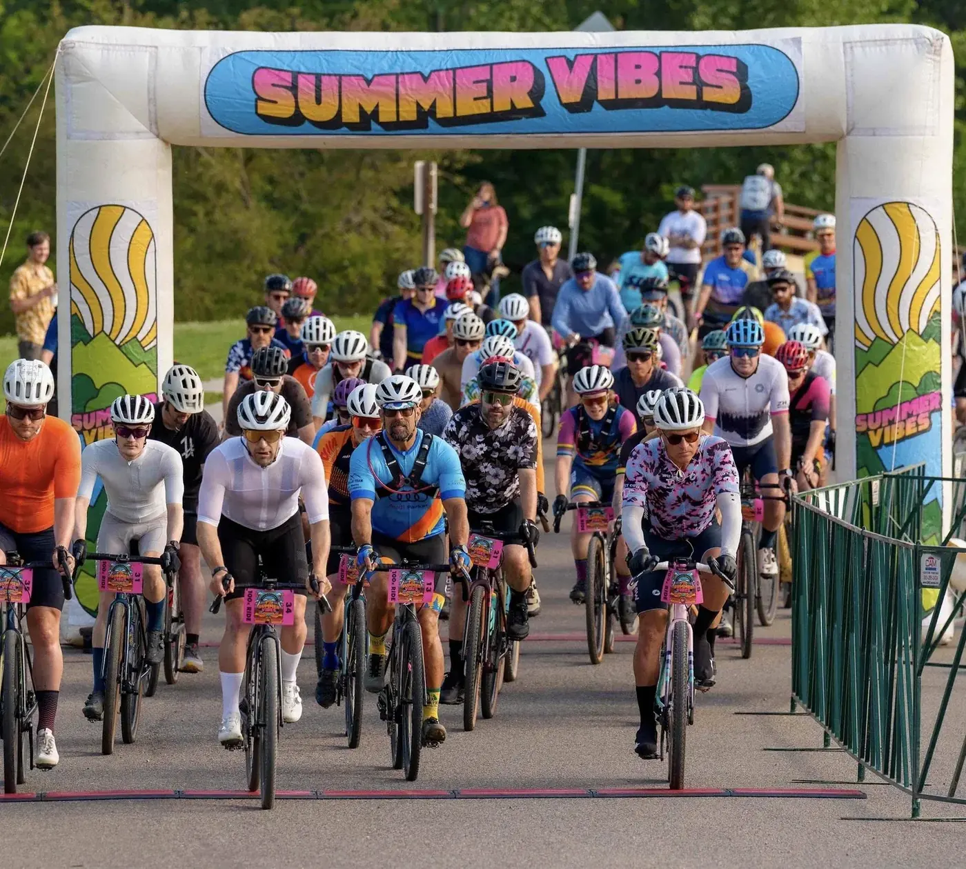 Hundreds of gravel riders rolling out under the Summer Vibes start arch