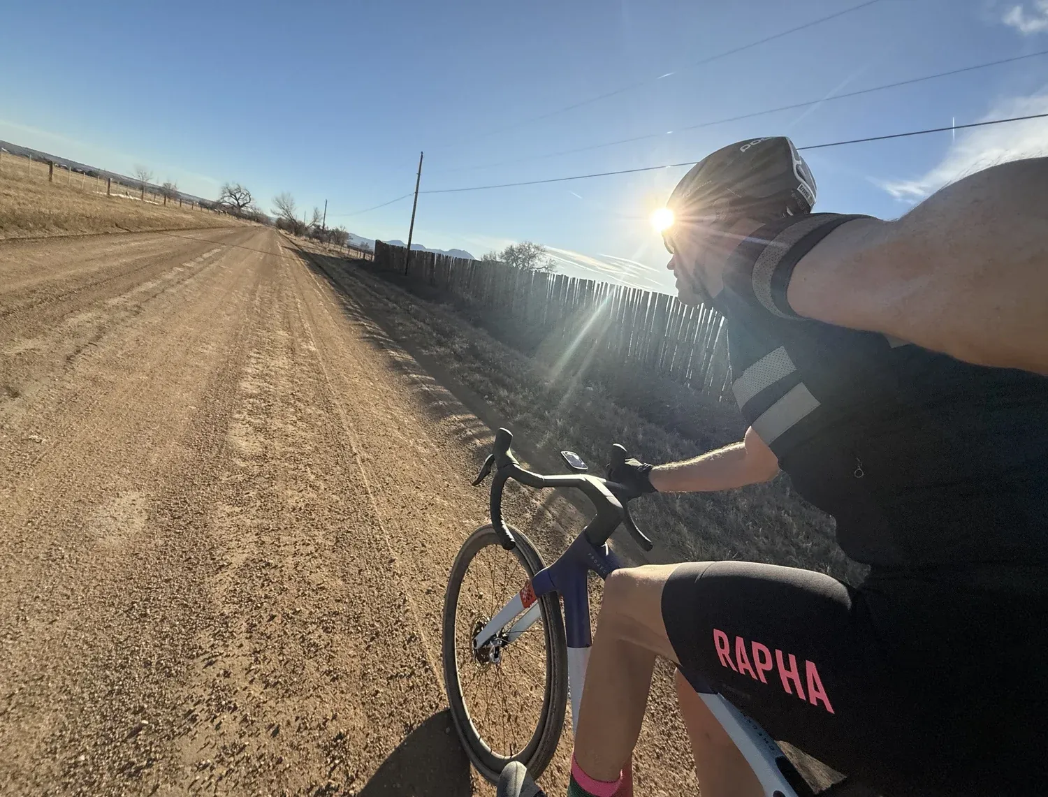 Rider on a straight gravel road with the sun behind